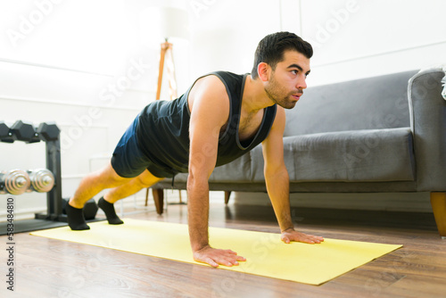 Attractive active man doing plank exercises at home