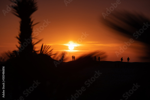 Obraz na płótnie Silhouette of people on a tropical beach enjoying the sunset. w salonie