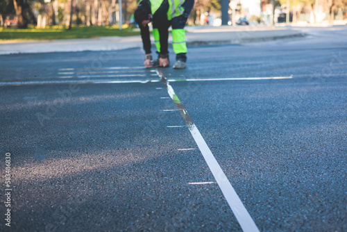 Process of making new road surface markings with a line striping machine  workers improve city infrastructure  demarcation marking of pedestrian crossing with a hot melted paint on asphalt pavement