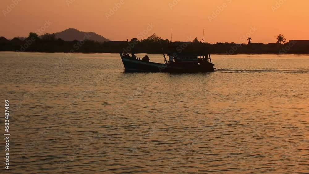Silhouette of a traditional khmer fishing boat sailing by on the horizon in Preaek Tuek Chhu river in the sleepy town of Kampot Cambodia Silhouette of a traditional khmer fishing boat sailing by on the horizon in Preaek Tuek Chhu river in the sleepy town of Kampot Cambodia