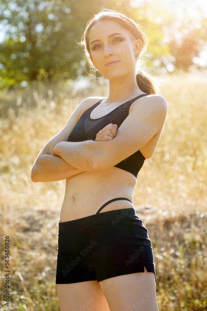 Attractive sporty young woman posing in sportswear on a sunny summer day in nature Attractive sporty young woman posing in sportswear on a sunny summer day in nature
