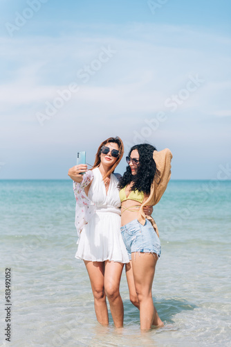 Travel summer concept, Cheerful young adult woman jumping on the beach, Happy friends relaxing on weekend together. © Platoo Studio