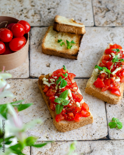 bruschetta with tomatoes, herbs and cheese on a stone surface, sandwiches with toasted bread and tomatoes for breakfast, snack