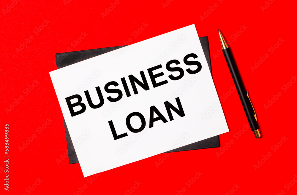 Black pen, envelope and white card with the text BUSINESS LOAN on a bright red background Black pen, envelope and white card with the text BUSINESS LOAN on a bright red background
