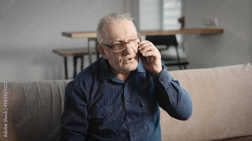 Elderly man at home, talking on the phone. A pensioner uses a smartphone to communicate with his family Elderly man at home, talking on the phone. A pensioner uses a smartphone to communicate with his family