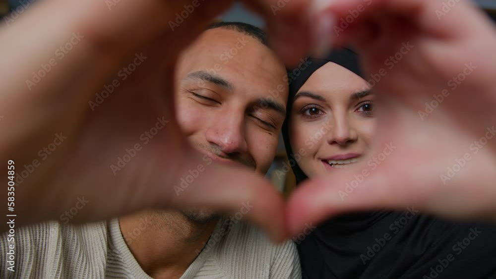 Multiracial ethnic couple african american man smiling muslim woman in hijab looking through joined fingers heart shape united hands frame Valentines Day romantic loving wife husband relationship love Multiracial ethnic couple african american man smiling muslim woman in hijab looking through joined fingers heart shape united hands frame Valentines Day romantic loving wife husband relationship love