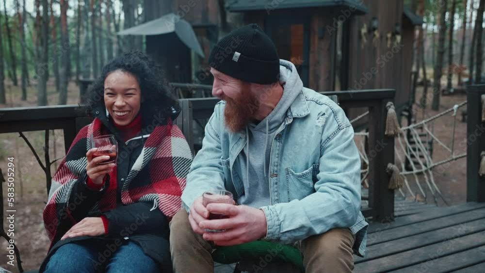 Multinational couple talking and drinking mulled wine in the forest Multinational couple talking and drinking mulled wine in the forest