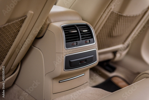 Deflectors for rear passengers. Luxury modern beige car interior, climate control, air ducts on car panel. Details interior inside closeup. Luggage net, pocket, mesh on the back of car driver seat.