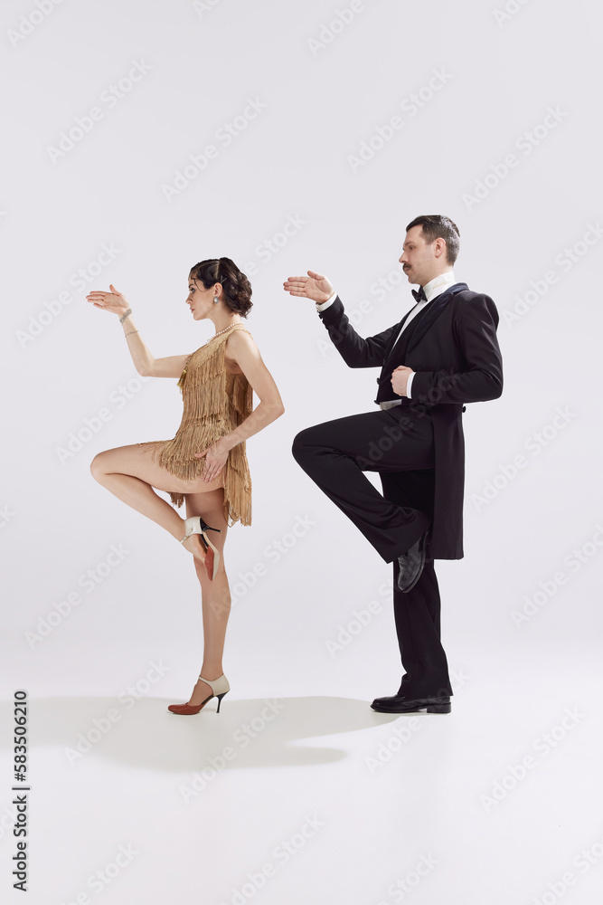 Chic couple of dancers in old-time evening costume dancing retro funny dance over white background. Love and music, vintage fashion concept Chic couple of dancers in old-time evening costume dancing retro funny dance over white background. Love and music, vintage fashion concept
