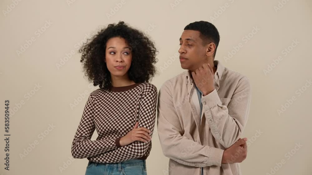 Confident African young couple thinking and looking at the camera while standing in the beige studio Confident African young couple thinking and looking at the camera while standing in the beige studio