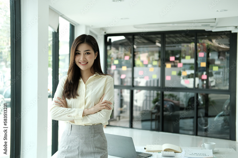 Happy young Asian saleswoman looking at camera welcoming client. Smiling woman executive manager, secretary offering professional business services holding digital tablet standing in office. Portrait Happy young Asian saleswoman looking at camera welcoming client. Smiling woman executive manager, secretary offering professional business services holding digital tablet standing in office. Portrait