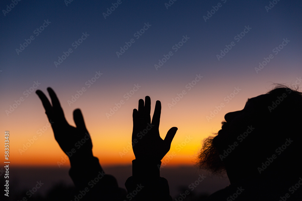 Silhouette of man kneeling down praying for worship God at sky background. Christians pray to jesus christ for calmness. In morning people got to a quiet place and prayed. copy space. Silhouette of man kneeling down praying for worship God at sky background. Christians pray to jesus christ for calmness. In morning people got to a quiet place and prayed. copy space.