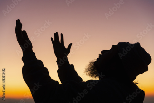 Silhouette of man kneeling down praying for worship God at sky background. Christians pray to jesus christ for calmness. In morning people got to a quiet place and prayed. copy space.