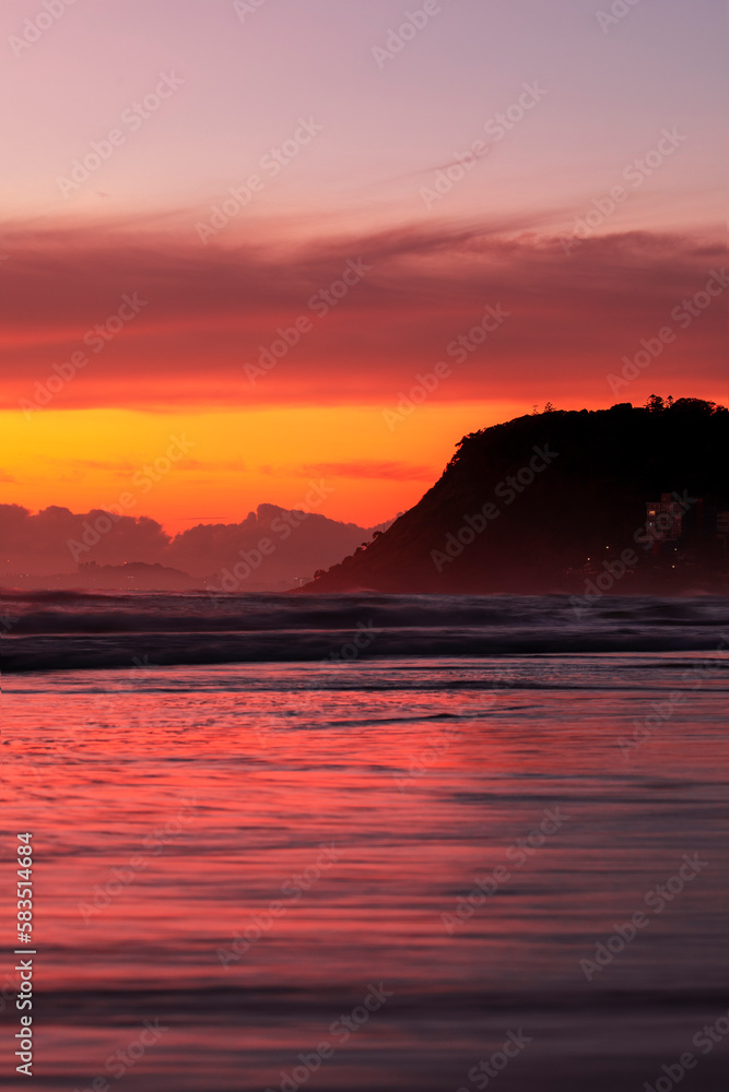 Beach view with colourful ocean sunrise and clouds and Burleigh Headland, Gold Coast Australia