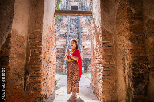 Photography young woman dressed in traditional red Thai dress and golden ornaments stands sa