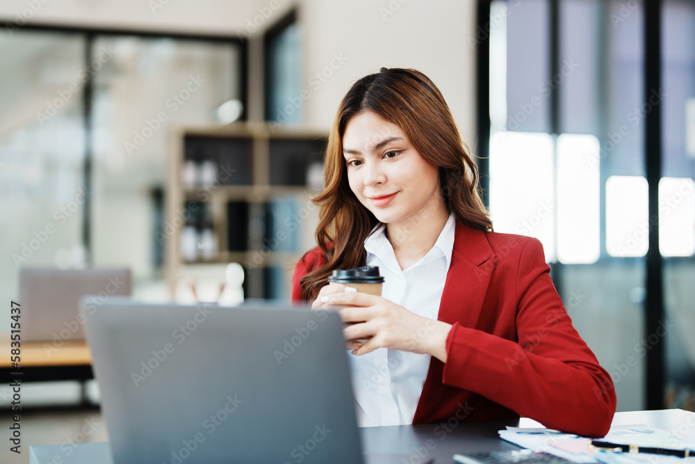 Beautiful young teen asian businesswomen using computer laptop and drink coffee with in smile winner is gesture, Happy to be successful celebrating achievement success