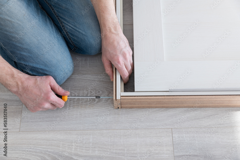 Worker tightens a door frame with a screw. Repair and decoration of apartments. Installation and installation of interior doors. Carpentry work. Working with a screwdriver. Worker tightens a door frame with a screw. Repair and decoration of apartments. Installation and installation of interior doors. Carpentry work. Working with a screwdriver.