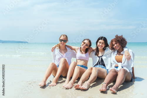 Group of diverse teenager friends sitting on the beach, spending time together on summer, Young girl enjoying with outdoor activity, Lifestyles on vacation concept. © Platoo Studio