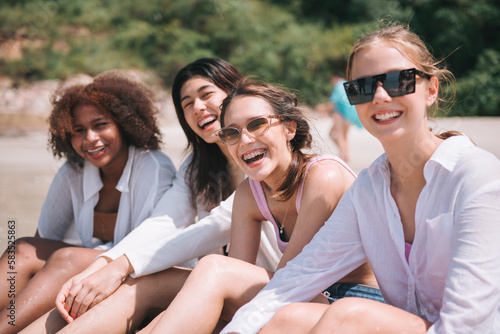 Group of diverse teenager friends sitting on the beach, spending time together on summer, Young girl enjoying with outdoor activity, Lifestyles on vacation concept.