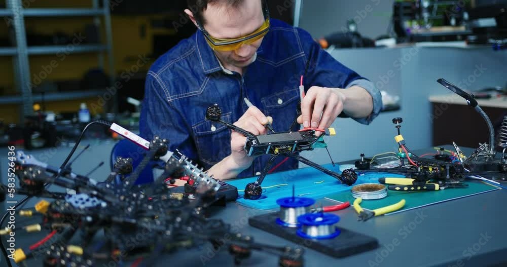 Engineer working on racing fpv drone combat kamikaze bomber in workshop. Engineer working on racing fpv drone combat kamikaze bomber in workshop.