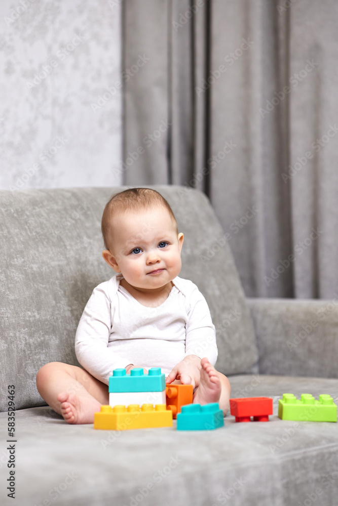 Naklejka premium baby girl playing with colorful toy blocks