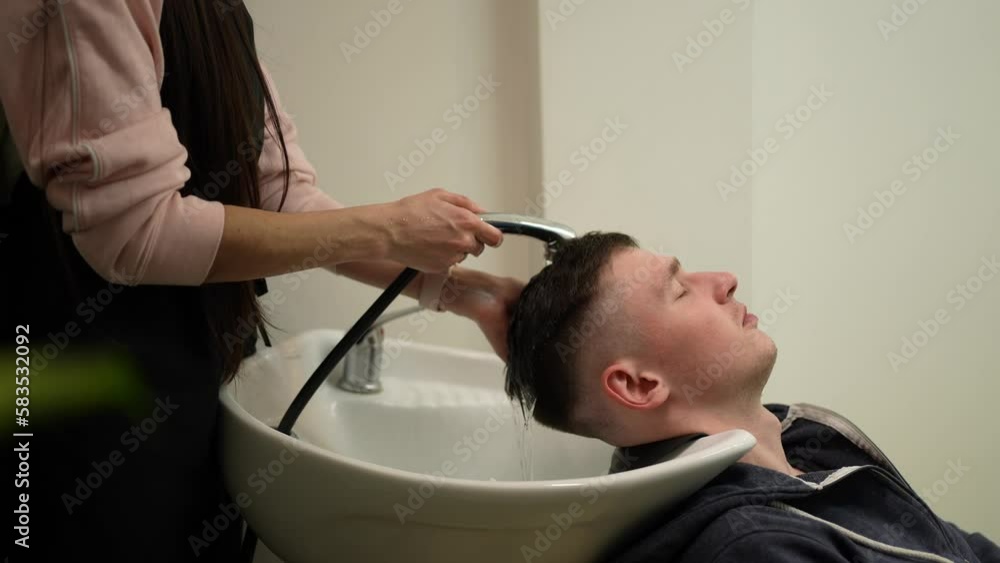 A hairdresser washes a client's head in a sink A hairdresser washes a client's head in a sink