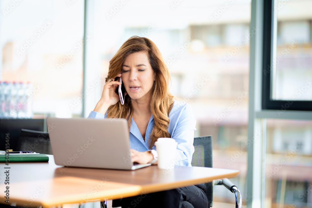 Shot of a business woman using laptop and working in a modern glass office Shot of a business woman using laptop and working in a modern glass office