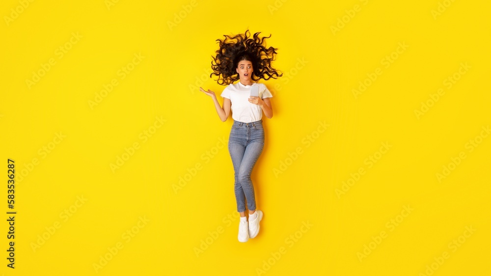 Shocked Female Using Smartphone Reading Message Posing Over Yellow Background