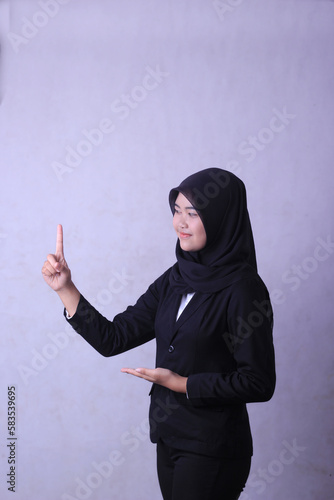 A woman in a black hijab points to the right. advertising concept