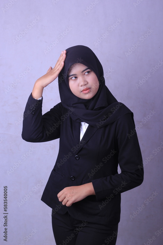 A woman in a black suit and a white shirt is standing in front of a gray background. A woman in a black suit and a white shirt is standing in front of a gray background.