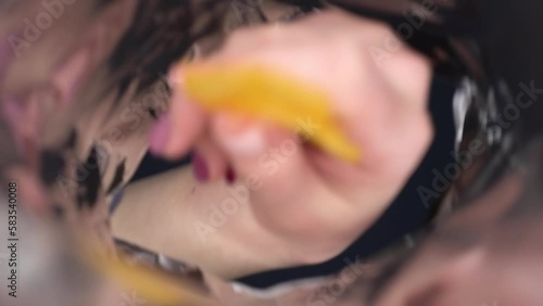 A young woman looks into a bag of crisps and eats them. View of a woman from a pack of chips.