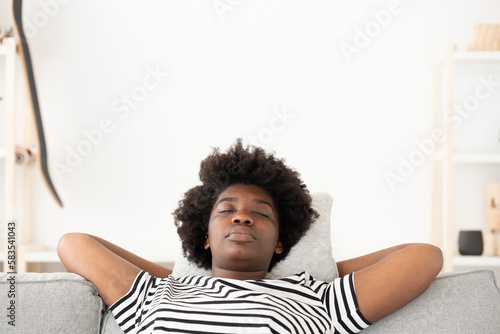 African American woman relaxing and dreaming on sofa with closed eyes with copy space