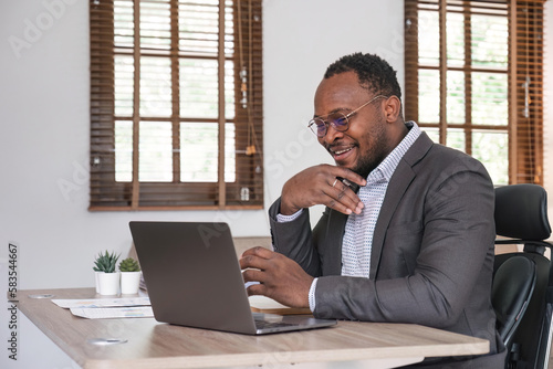 African American businessman using his laptop computer while working remotely from home. Online working or learning concept