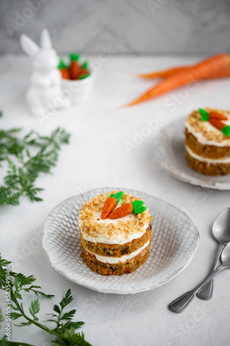 Easter Carrot cake with cream cheese frosting and marzipan decorations on a white stone background for festive dinner. Small easter bento cake. Fresh homemade carrot cake. Traditional Easter food. 