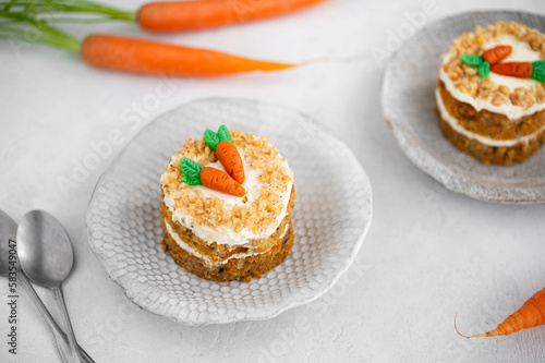 Easter Carrot cake with cream cheese frosting and marzipan decorations on a white stone background for festive dinner. Small easter bento cake. Fresh homemade carrot cake. Traditional Easter food. 