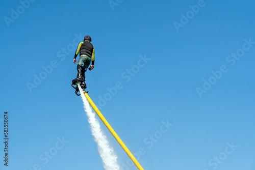 man flies on a FlyBoard against the background of the blue sky. Extreme sport