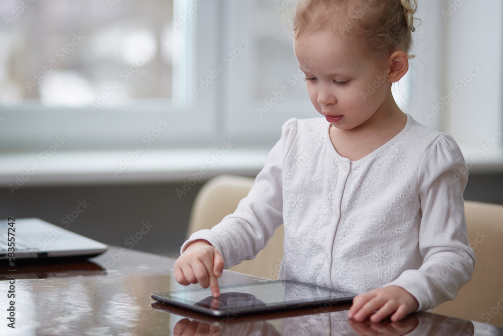 A preschooler girl uses a tablet for learning and entertainment. Modern education. Copy space A preschooler girl uses a tablet for learning and entertainment. Modern education. Copy space