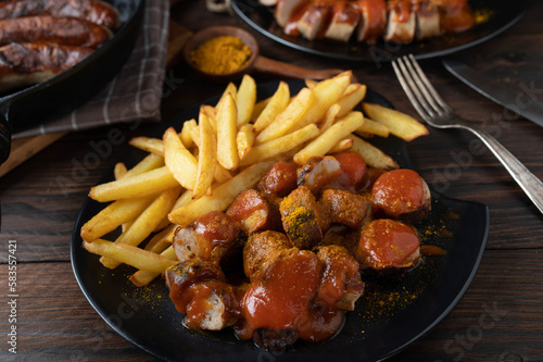 Curry Sausage with french fries on rustic and wooden table background.