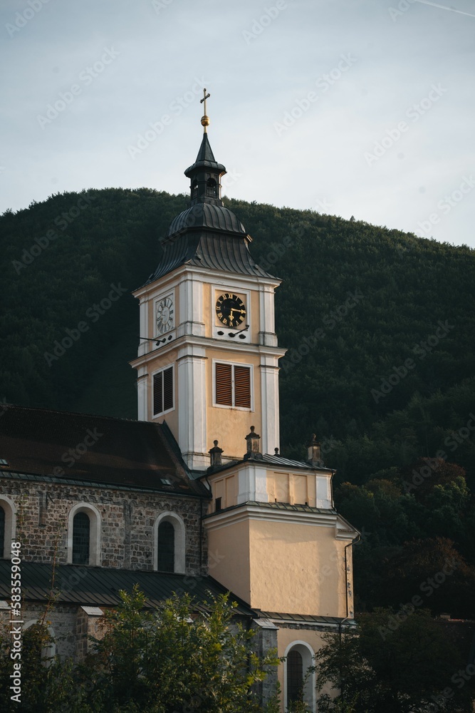 Vertical shot of a Clock tower of a monastery in the town of Lilienfeld with mount behind in Austria