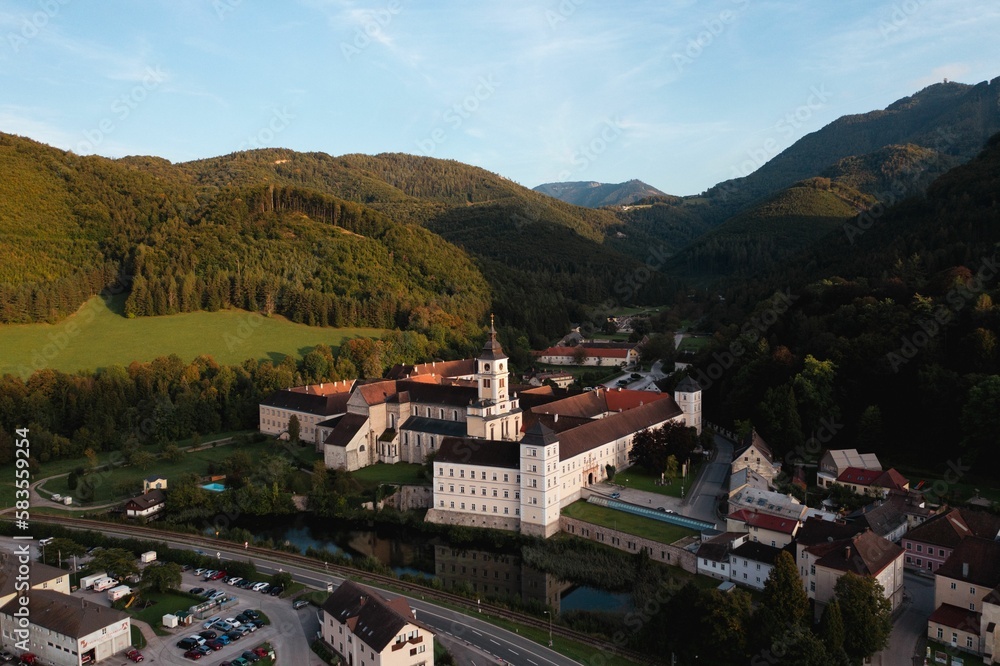 Drone shot of a monastery in the town of Lilienfeld with mountain behind and river in Austria