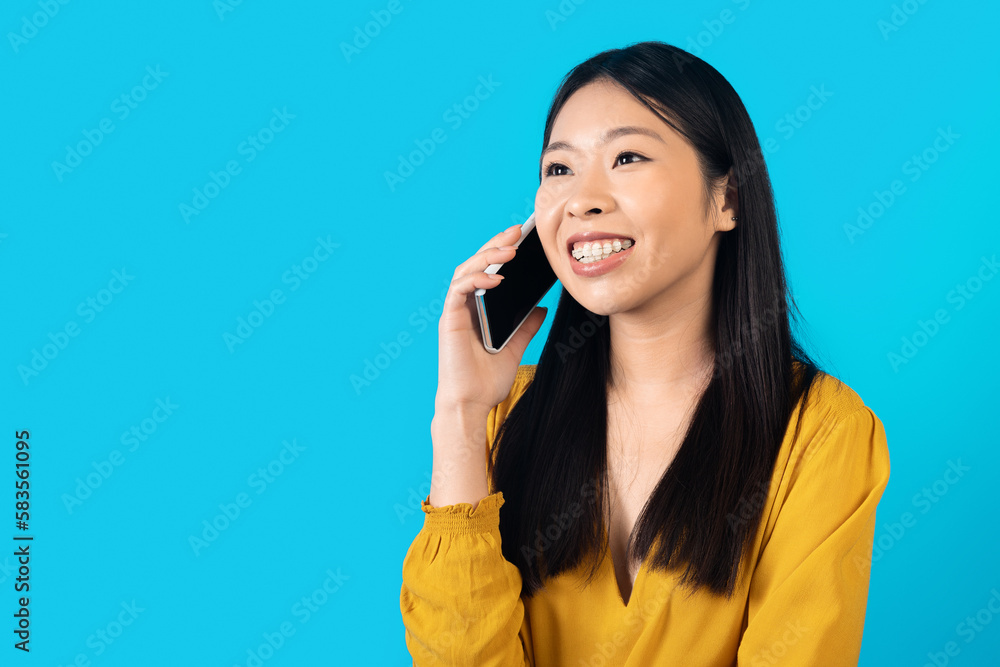 Chatty happy young asian woman have phone conversation on blue Chatty happy young asian woman have phone conversation on blue