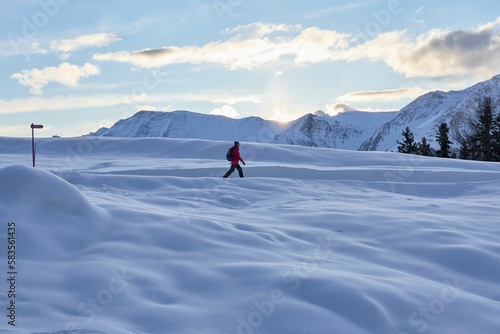 Man hikes snowy trails in Swiss Alps at dawn in winter