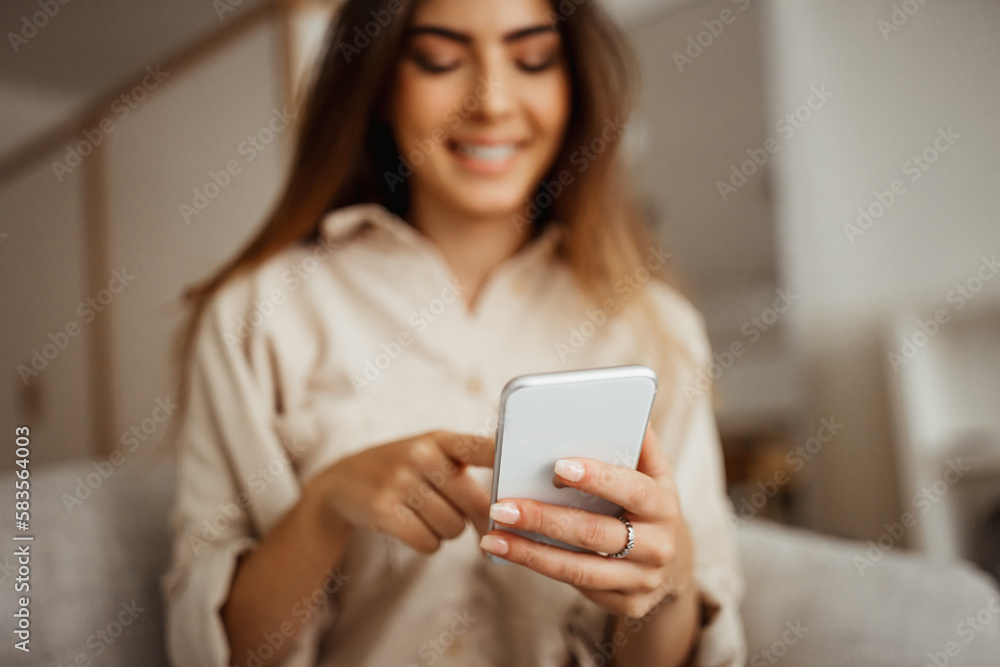 Cheerful millennial mixed race female looking at phone, reading message, chatting in room interior, blurred Cheerful millennial mixed race female looking at phone, reading message, chatting in room interior, blurred