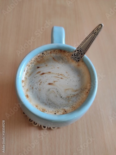 Blue clay cup with coffee with a spoon on a wooden background