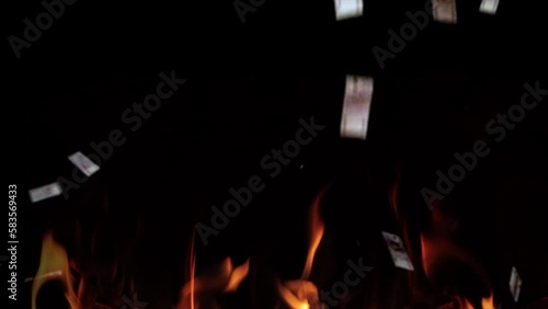 Money falling into the fire on a black background