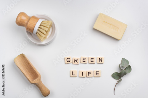 sustainable lifestyle concept flat lay with bamboo brush, wooden scoop, soap bar and green leaves. GREEN LIFE written with tile letters 