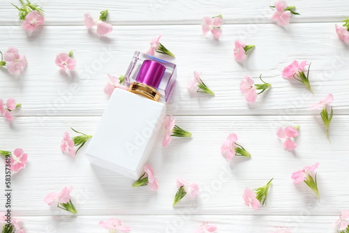 White glass perfume bottle on pink floral background, mockup