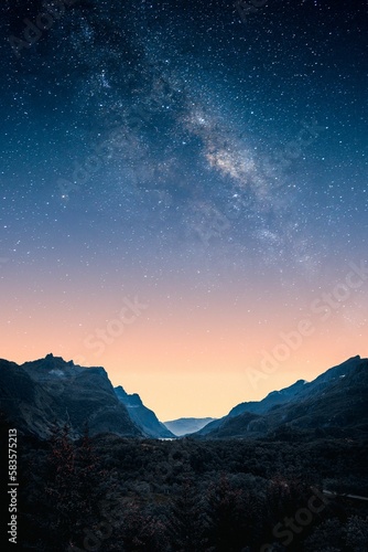Vertical shot of the mesmerizing starry sky over the hills at sunset