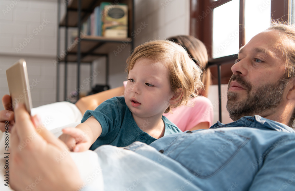Little boy's father read stories to children before going to bed to unwind and sleep soundly until the morning. Little boy's father read stories to children before going to bed to unwind and sleep soundly until the morning.
