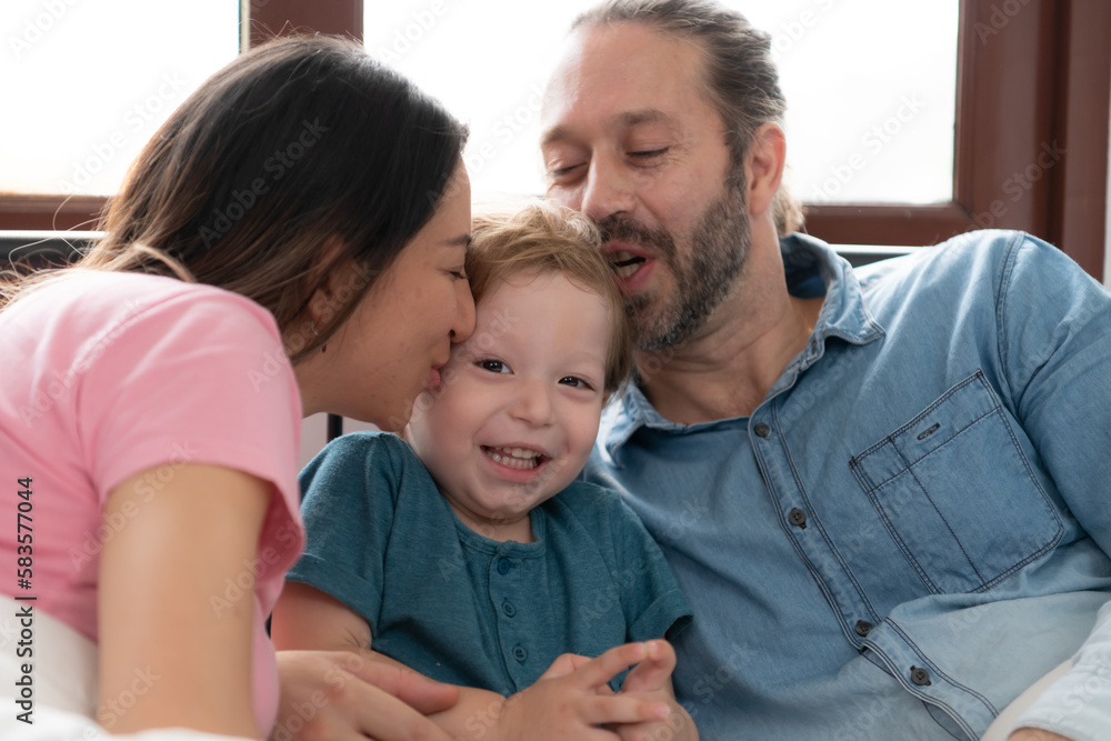 After the little boy wakes up from his nap, his father and mother engage in enjoyable activities in his bedroom. After the little boy wakes up from his nap, his father and mother engage in enjoyable activities in his bedroom.